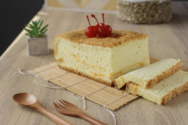 Popolare dessert giapponese o pan di spagna di castella con ciliegina sulla torta servito su un tavolo di legno