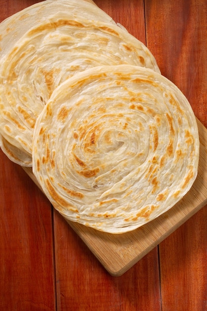 Porotta fatta in casa o focaccia a strati realizzata con farina di grano tenero o per tutti gli usi disposta su una base di legno isolata e vista dall'alto