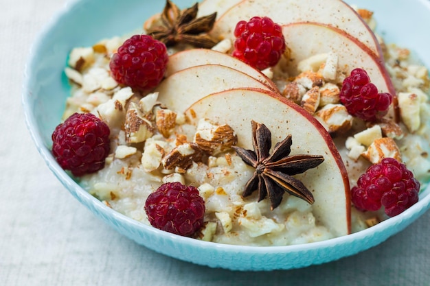 Porride di avena sano e gustoso servito con lamponi freschi cannella anice e fette di mela Il cibo in stile fitness è la scelta migliore per rimanere in salute e pieni di energia