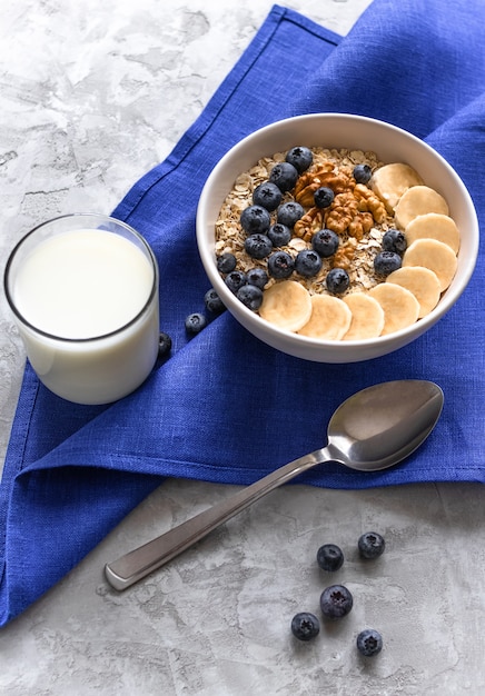 Porridge con banane, mirtilli e noci e bicchiere di latte per una sana colazione o pranzo.