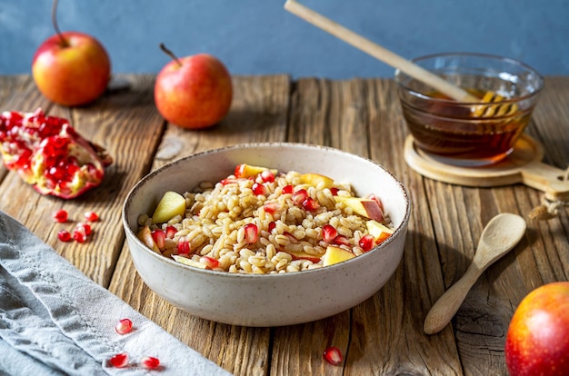 Porridge d'orzo dolce fatto in casa con semi di melograno, mele e miele Celebrazione di Rosh Hashanah