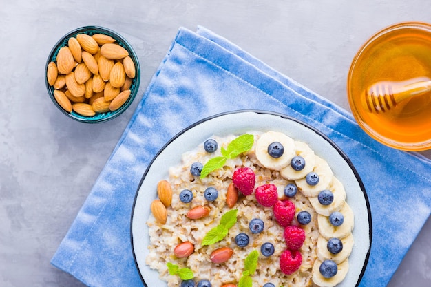 Porridge di avena con bacche, frutta e miele su sfondo grigio, avena gustosa con lamponi