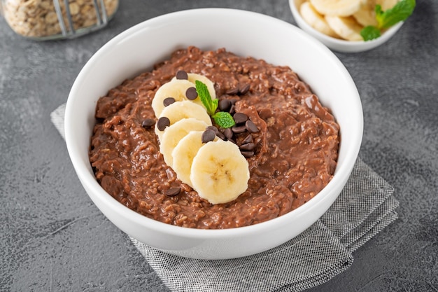 Porridge di farina d'avena al cioccolato con banana e gocce di cioccolato in cima Colazione sana Copia spazio