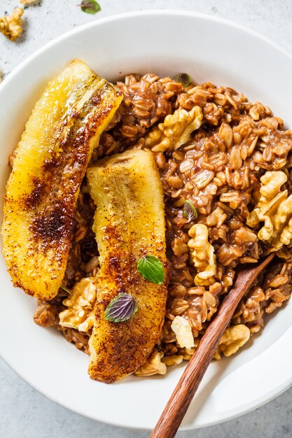 Porridge di farina d'avena al cioccolato con banana fritta e noce in zolla bianca.