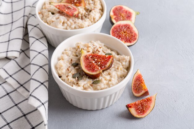 Porridge di farina d'avena con fichi e semi. Sfondo grigio. Cibo sano per la colazione.