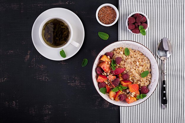 Porridge di farina d'avena con lamponi e pesche su sfondo scuro Colazione sana Cibo vegetariano Vista superiore