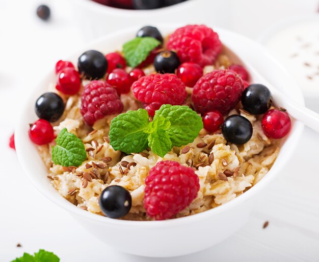 Porridge di farina d&#39;avena gustoso e sano con bacche, semi di lino e yogurt.