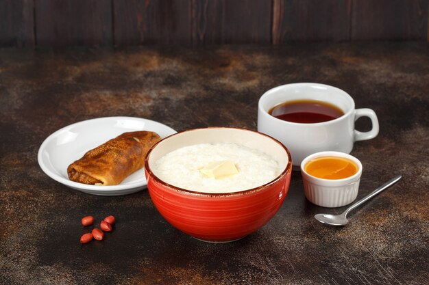 Porridge di farina d'avena in una ciotola, crepe ripiena e tè