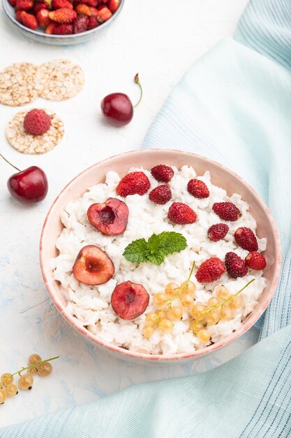 Porridge di fiocchi di riso con latte e fragola in ciotola di ceramica su sfondo di cemento bianco Vista laterale