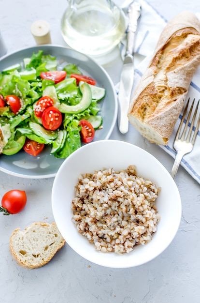 Porridge di grano saraceno caldo con burro fuso nel piatto e insalata di verdure per il pranzo sul tavolo