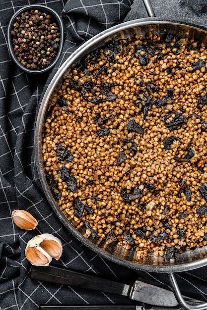 Porridge di grano saraceno con funghi. Cibo vegano. Cucina russa e ucraina. Sfondo nero. Vista dall'alto. Copia spazio