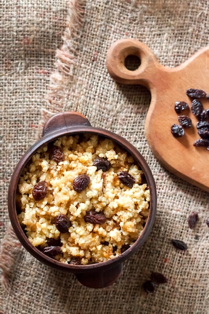 Porridge di miglio dolce con uvetta scura in ciotola rustica in ceramica