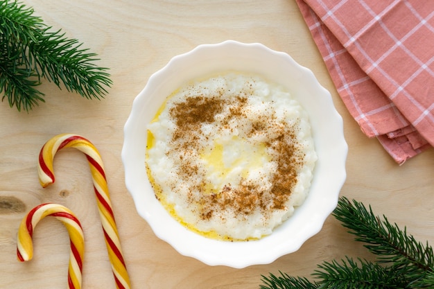 Porridge di riso di Natale con burro e cannella su fondo di legno, vista dall'alto.