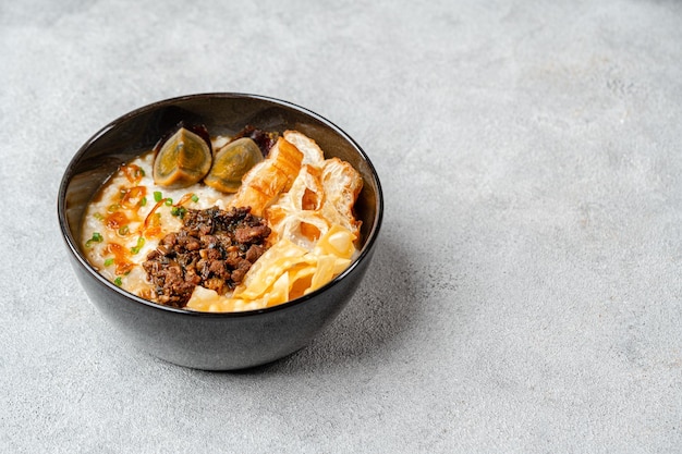 Porridge di riso o congee con uovo di maiale macinato e cakwe in una ciotola