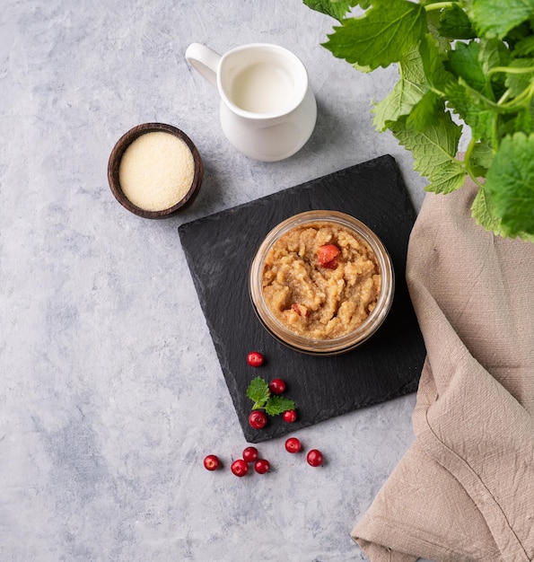 Porridge di semolina con mirtillo in un barattolo con latte e bacche su uno sfondo chiaro Il concetto di un alimento sano e dietetico