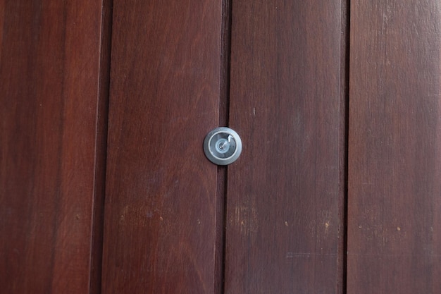 Porta dell'occhio del primo piano sullo spioncino grigio del fondo di legno