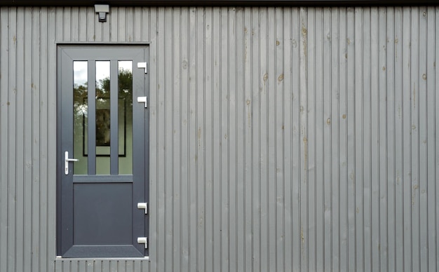 Porta di casa grigia con vetro sullo spazio della copia della parete del pannello verniciato grigio