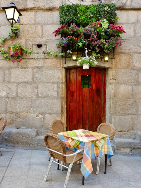 Porta di legno circondata da fiori e tavolo con sedie nel centro di Madrid Spagna