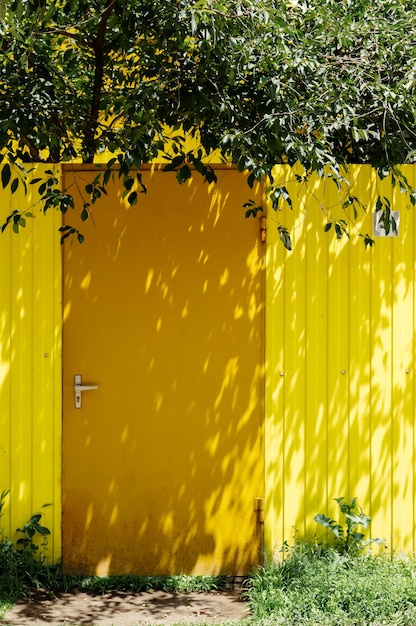 Porta gialla brillante e recinzione gialla con ciliegio. Settore privato nel sud della Russia