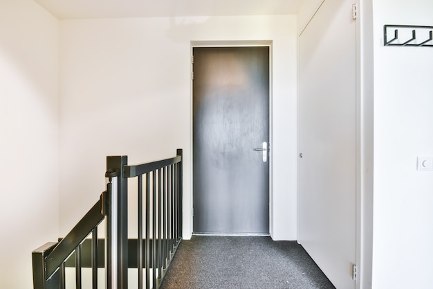 Porta grigia chiusa della stanza situata in cima alle scale in casa moderna
