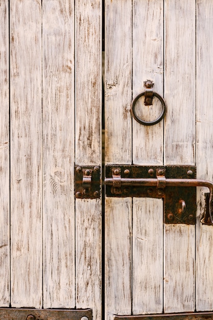 Porta in legno con catenaccio in metallo e maniglia ad anello