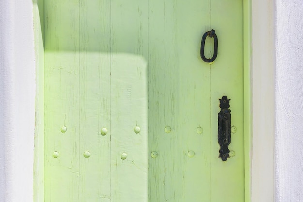 Porta in legno d'epoca dipinta di verde con maniglia in metallo da vicino.