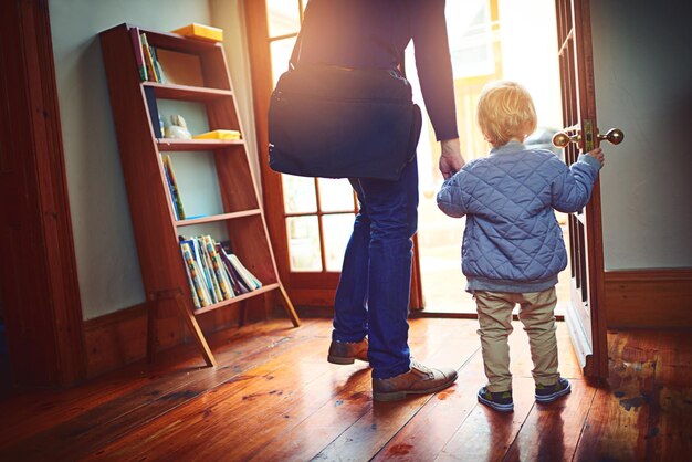 Porta posteriore o uscita con il genitore e il bambino in casa insieme per l'inizio della giornata o della mattina Entrata in famiglia o tenendo per mano la persona e il bambino nell'appartamento per la scuola o gli affari da dietro
