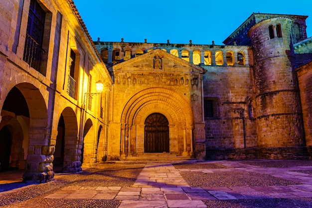 Porta principale di accesso alla chiesa medievale con torre e finestre ad arco. Santillana del Mar.