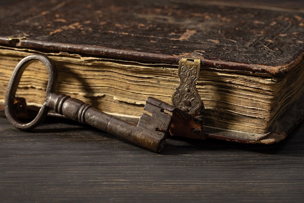 Porta vecchia chiave di metallo accanto a un libro antico sui fermagli Oggetti retrò su un tavolo scuro studio shot