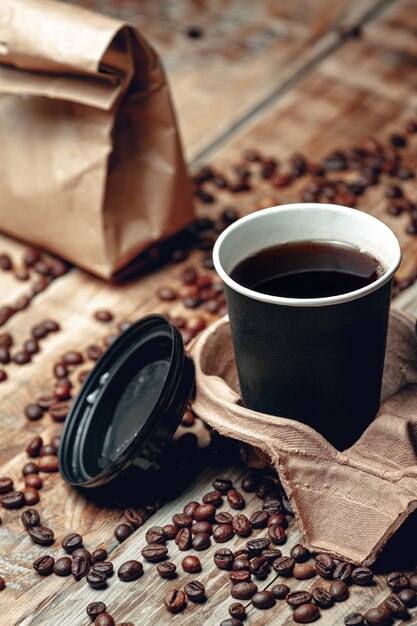 Porta via la tazza di caffè ed i chicchi di caffè su fondo di legno