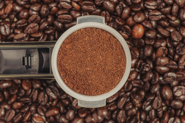 Portafiltro per macchina da caffè espresso su sfondo di chicchi di caffè.