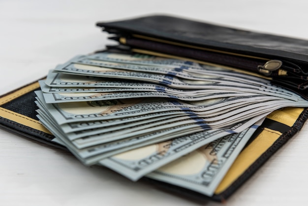 Portafoglio da uomo in pelle scura con banconote da un dollaro come sfondo finanziario, concetto di risparmio saving