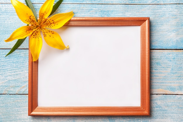 Portafoto in legno marrone con giglio di fiori gialli su sfondo blu squallido vecchio.