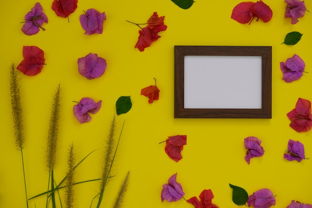 Portafoto mock-up con spazio per testo o immagine su sfondo giallo e fiori tropicali.