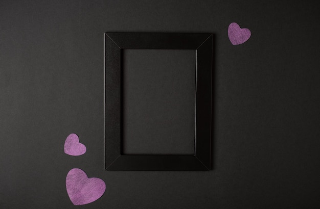 Portafoto nero con cuori rosa sui lati su sfondo nero. Vista piana laico e dall'alto. Concetto di San Valentino.