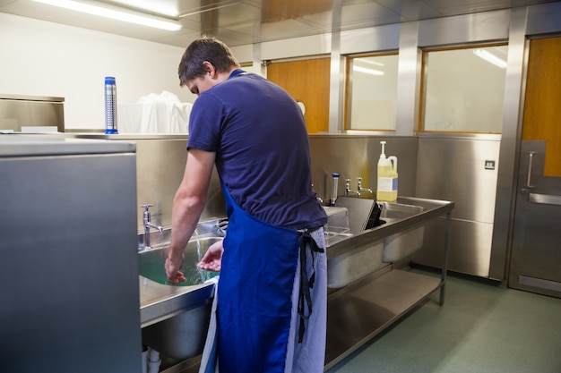 Portiere della cucina che lava al lavandino