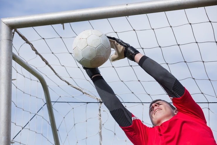 Foto portiere in rosso che salta in alto per salvare un gol