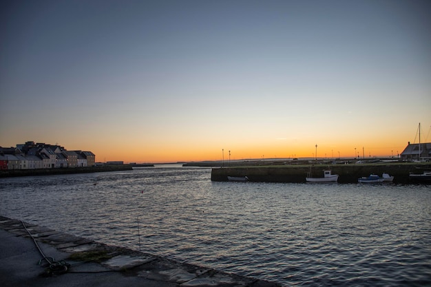 Porto di galway nella fredda mattina d'inverno con il sorgere del sole e il cielo limpido e il volo degli uccelli solitari