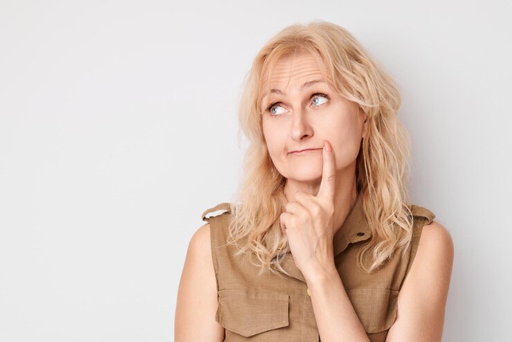 Portrait of clever mature woman touching chin thinking chooses doubts isolated on white studio background with copy space