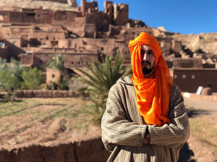 Photo portrait of man wearing headscarf while standing at desert