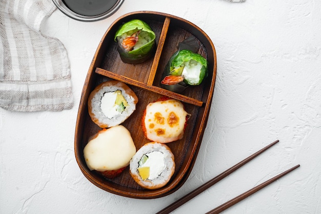 Porzione di cibo fresco in bento box giapponese con set di rotoli di sushi, su sfondo di pietra bianca, vista dall'alto piatta, con copyspace e spazio per il testo