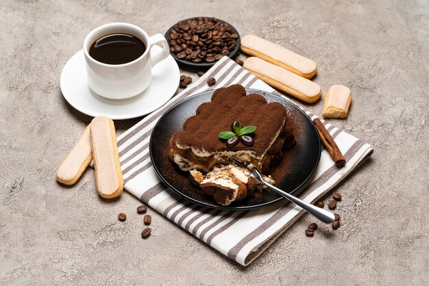 porzione di classico dessert tiramisù e biscotti savoiardi su sfondo di cemento