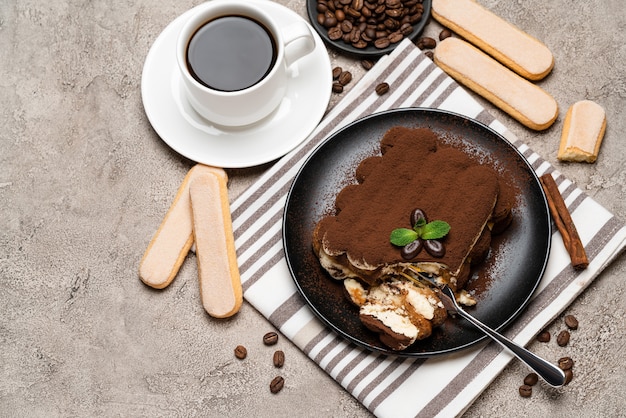 porzione di classico dessert tiramisù e biscotti savoiardi su sfondo di cemento