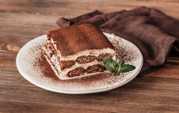 Porzione di dessert italiano di tiramisù su fondo di legno