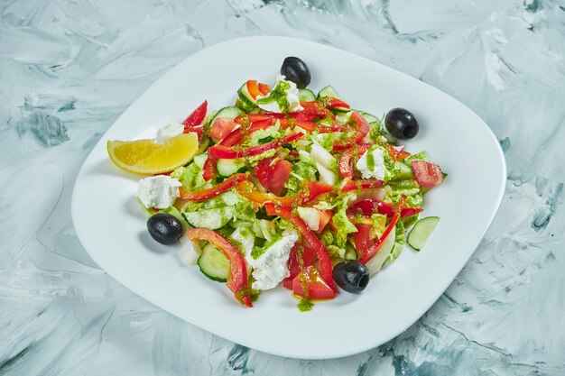 Porzione di insalata greca con feta su un piatto bianco. Cibo vegano sano ed equilibrato