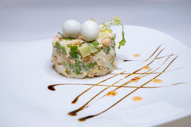 Porzione di insalata olivier su un piatto bianco Cetrioli salsiccia carote maionese Un piatto tradizionale Cucina russa Tavola di capodanno Menu del ristorante