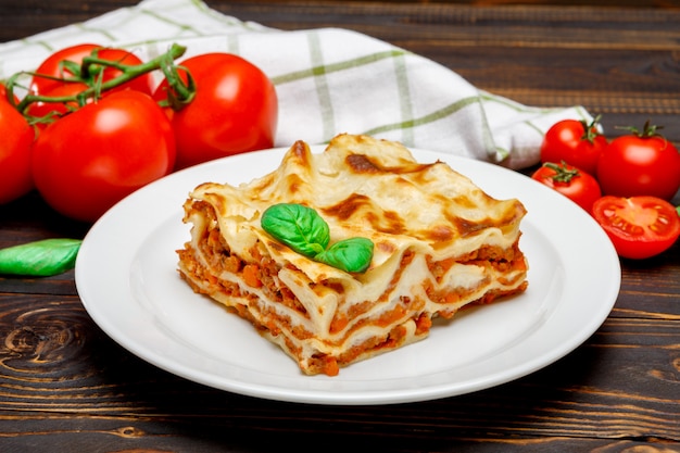 Porzione di lasagne al forno saporite su backgound di legno