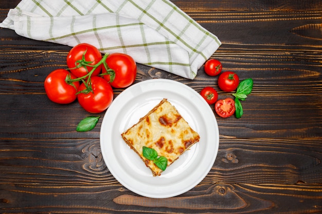 Porzione di lasagne al forno saporite su backgound di legno