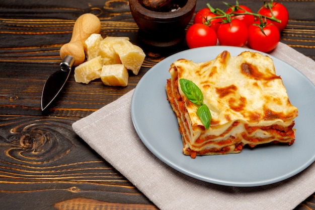 Porzione di lasagne al forno saporite su backgound di legno