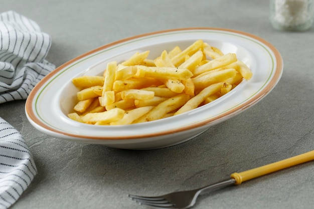 Porzione di patatine fritte sulla piastra bianca da vicino